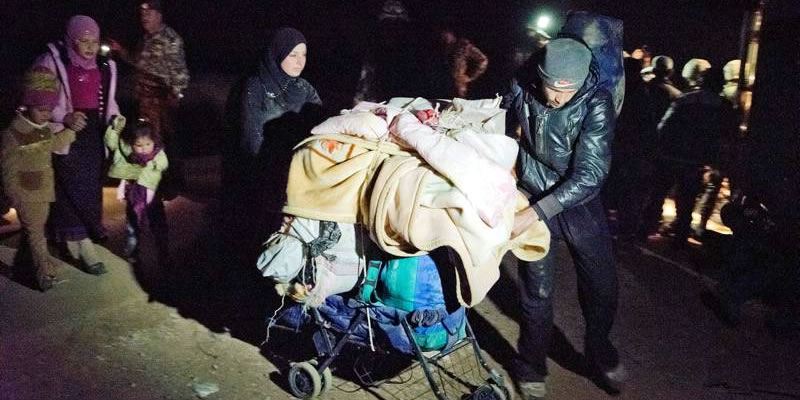 A man and his wife use a stroller to carry essential possessions across the border at night.